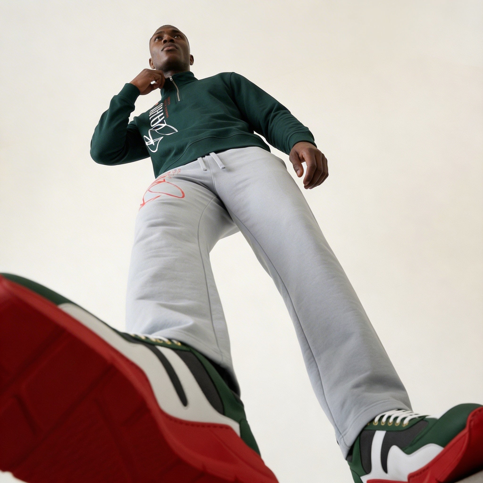 Person wearing a green sweater and gray pants with a white background