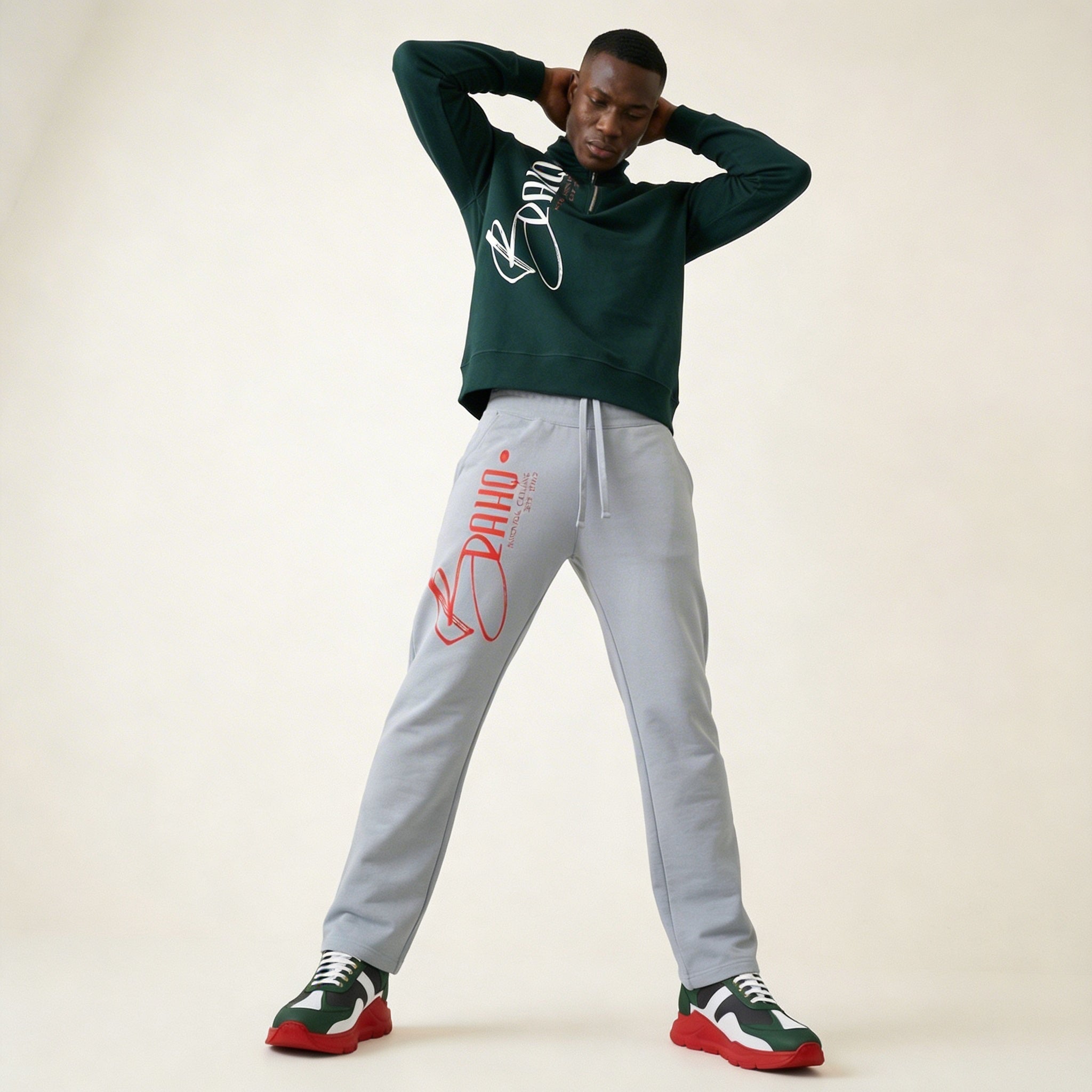 Person wearing a green hoodie and gray sweatpants with branding, standing against a plain background