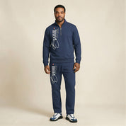 Man wearing a navy tracksuit with branding on a beige background