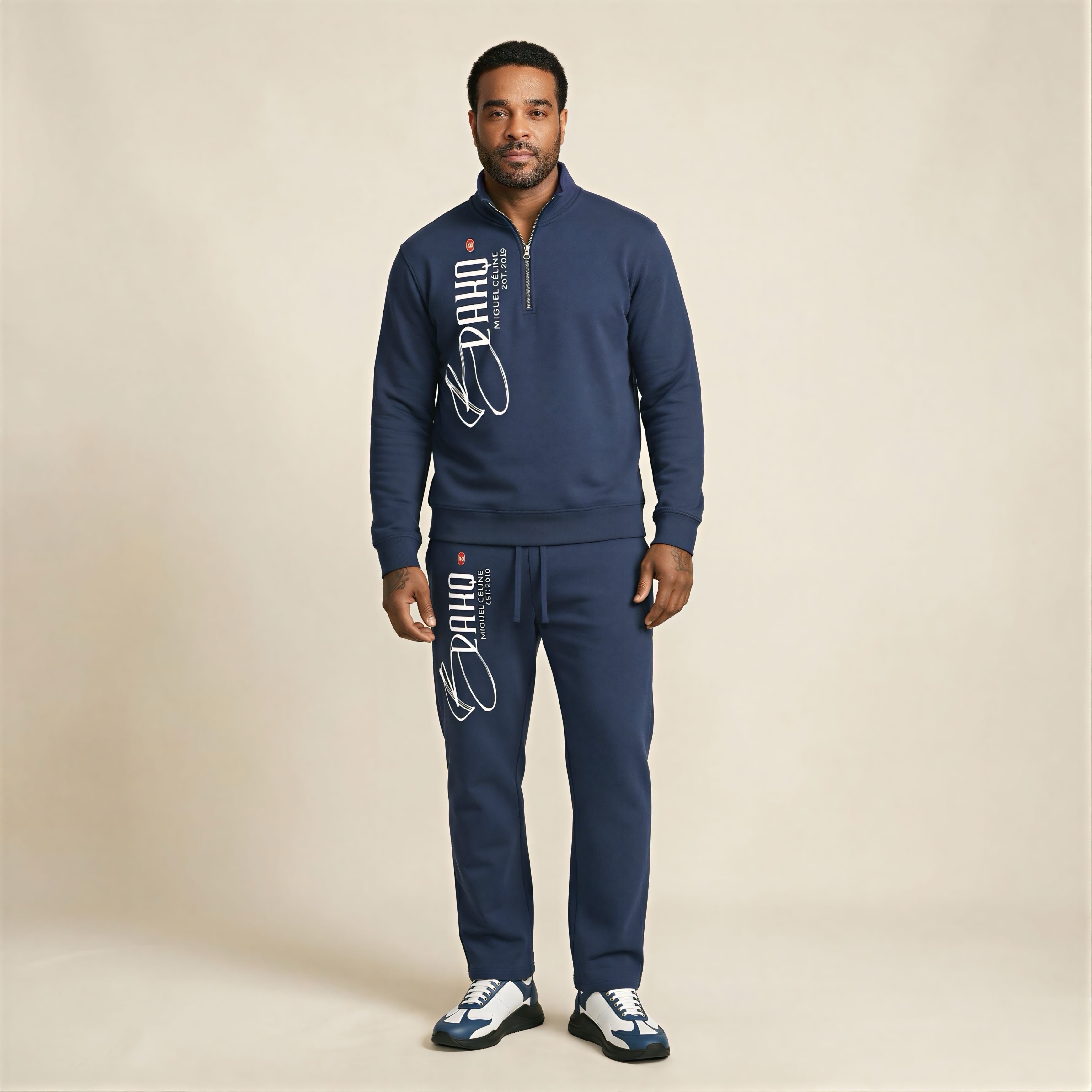 Man wearing a navy tracksuit with branding on a beige background