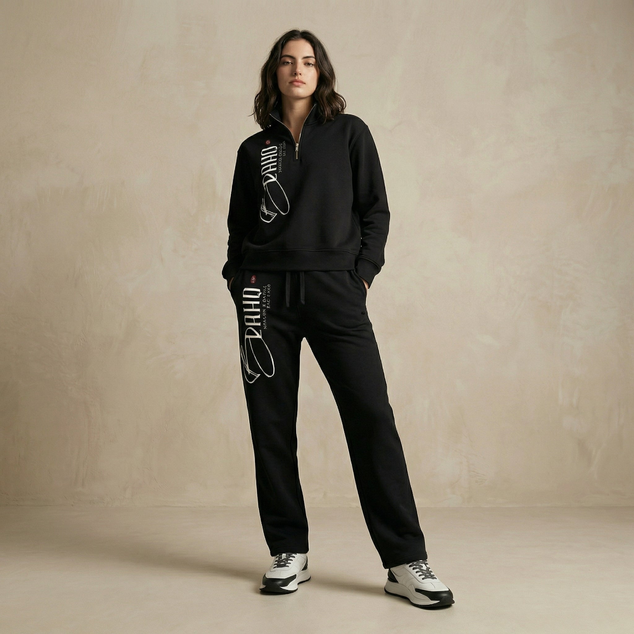Person wearing a black tracksuit with brand logo on a beige background