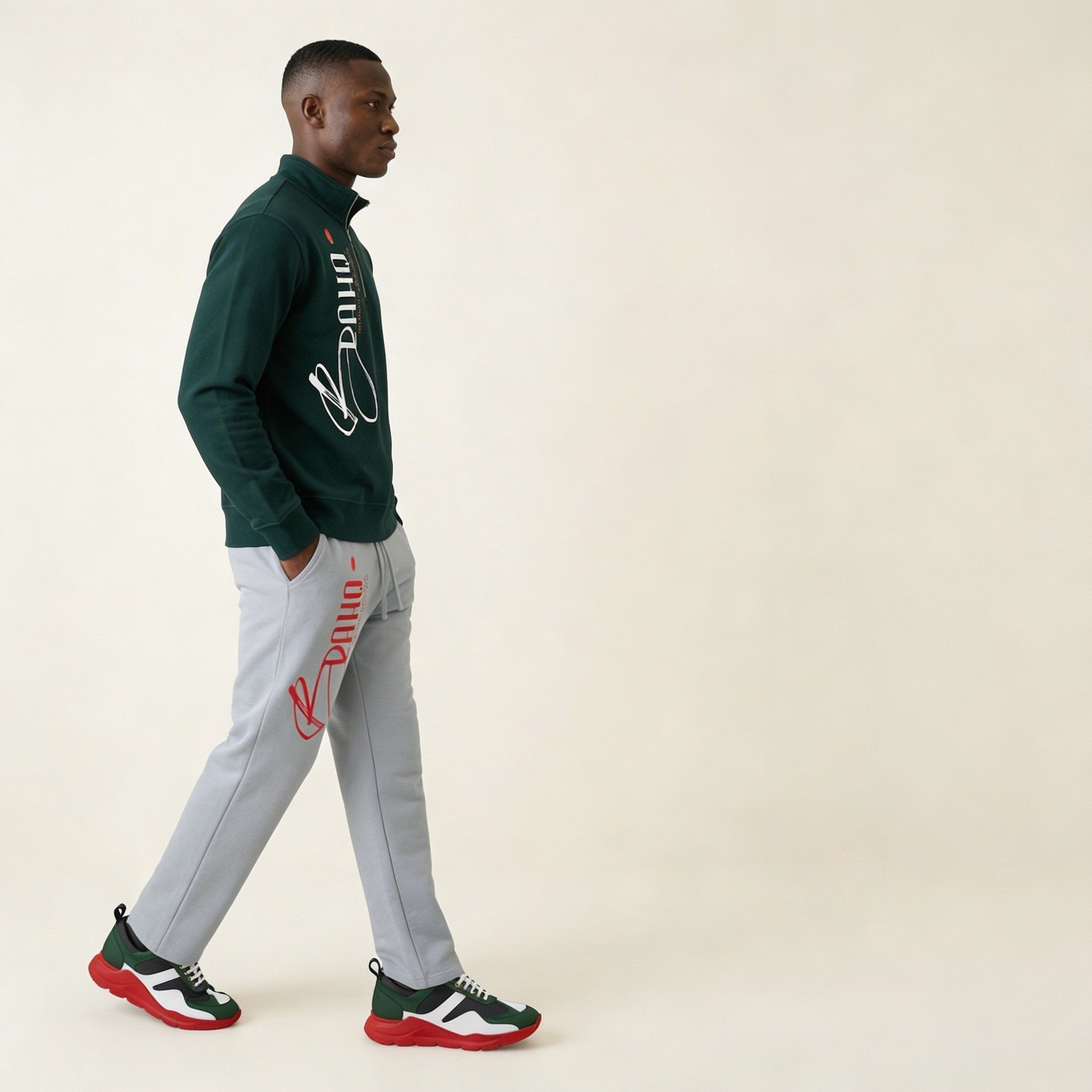 Man wearing a green jacket and gray pants with brand logos, walking on a beige background