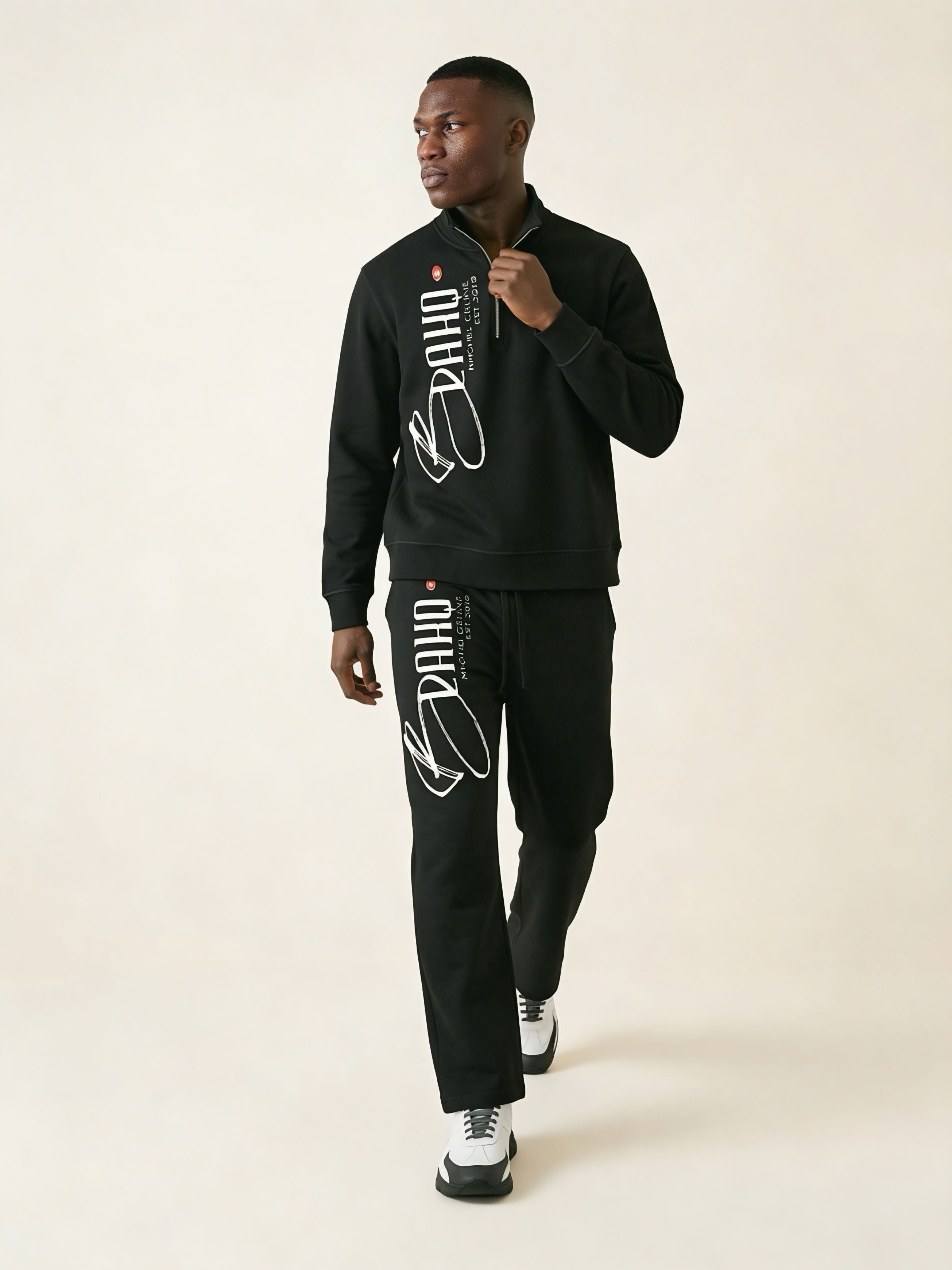 Person wearing a black tracksuit with brand logo on a white background