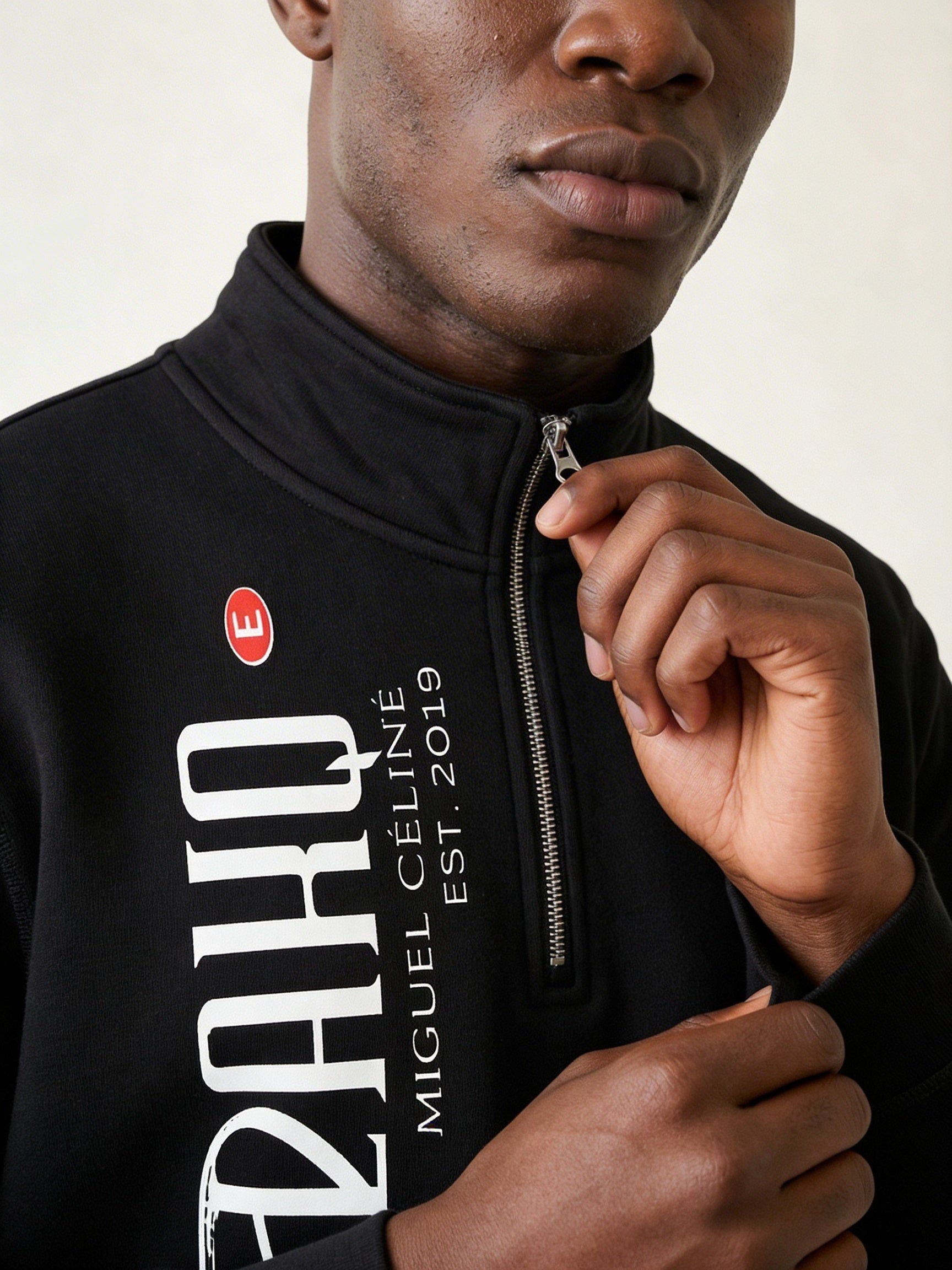Person wearing a black jacket with white text and a red logo.