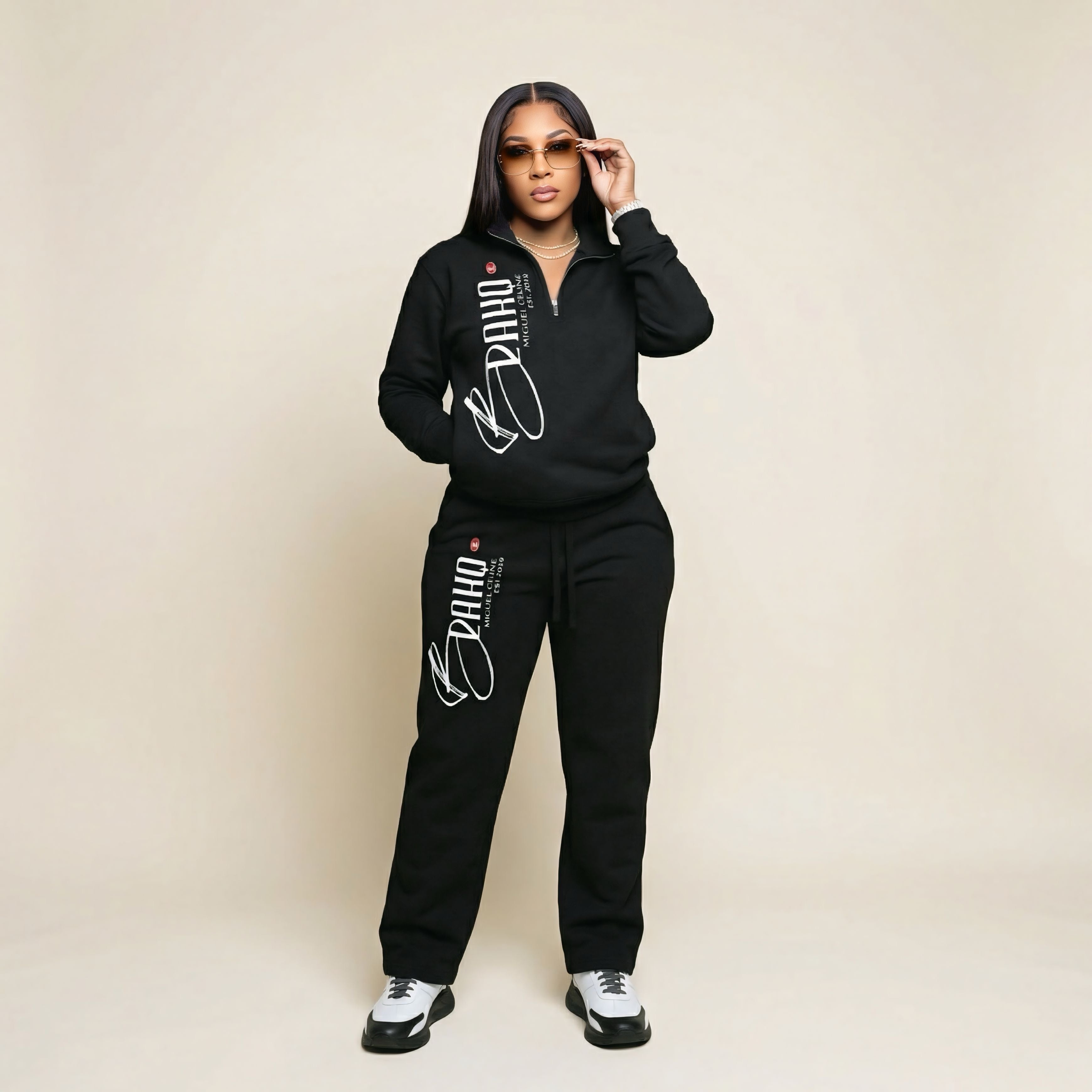 Person wearing a black tracksuit with branding on a beige background