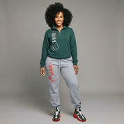 Woman wearing a green sweatshirt and gray sweatpants with red text on a gray background