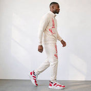 Man wearing a cream tracksuit with red branding against a white background