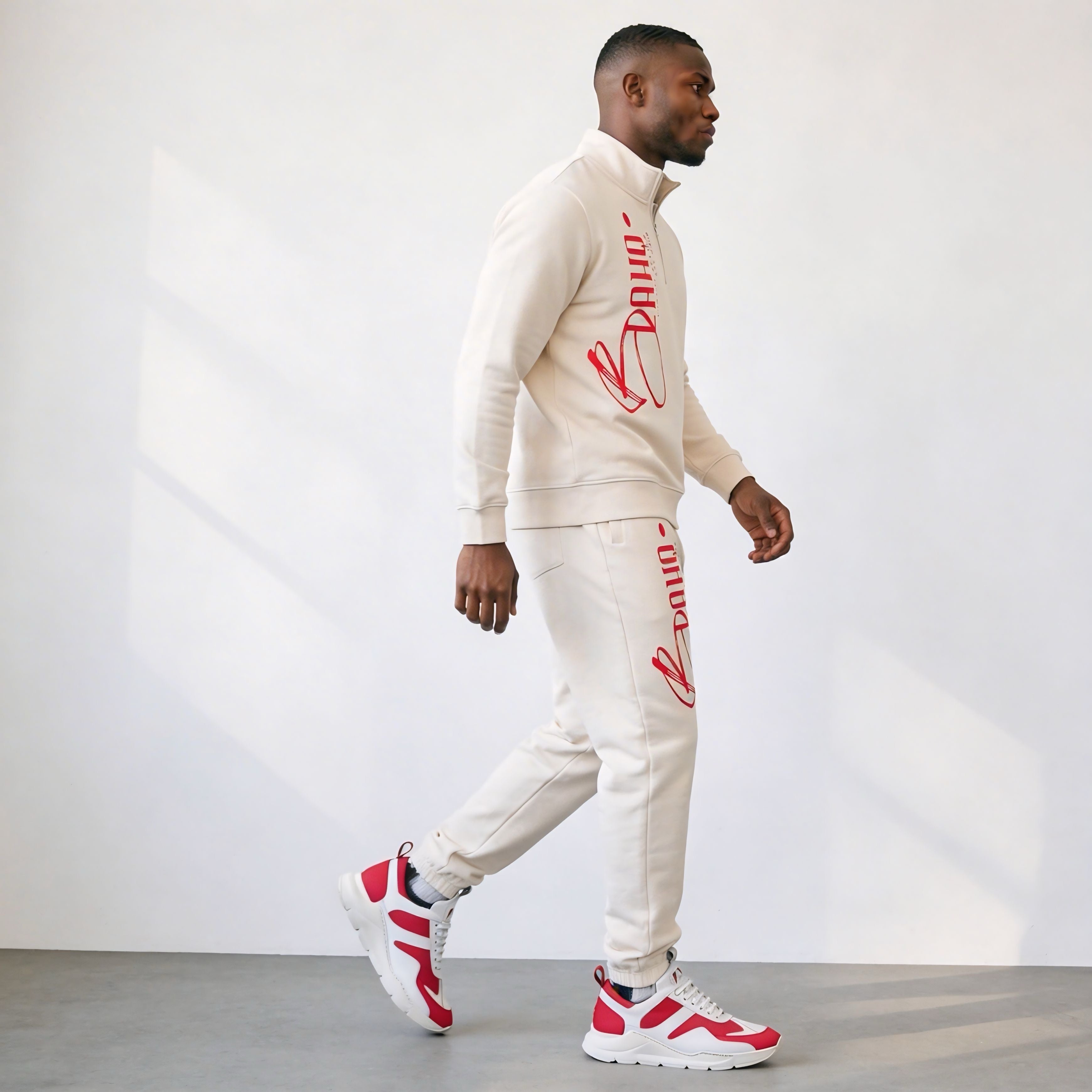 Man wearing a cream tracksuit with red branding against a white background