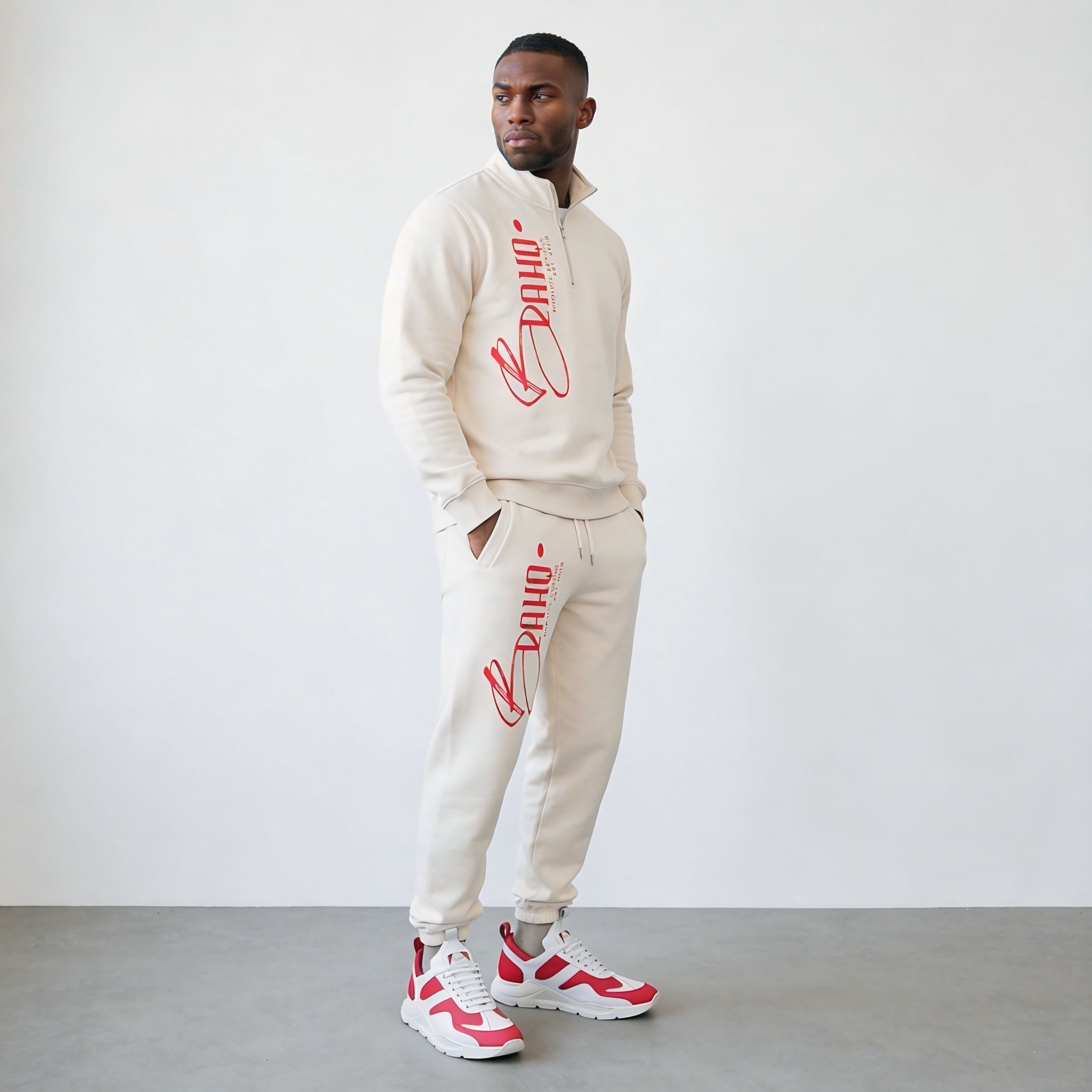 Man wearing a beige tracksuit with red branding against a white background