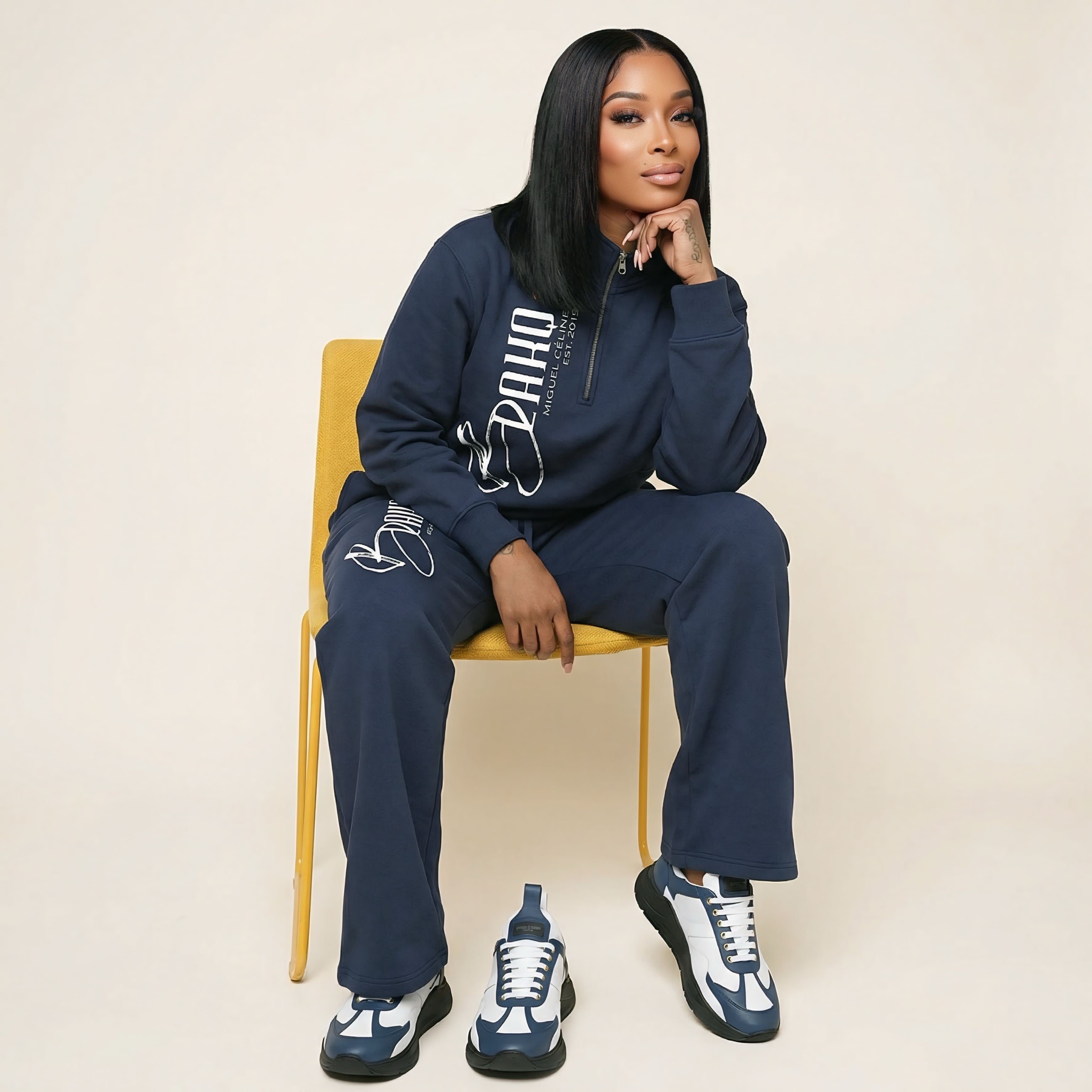 Woman sitting on a chair wearing a navy tracksuit with white accents.